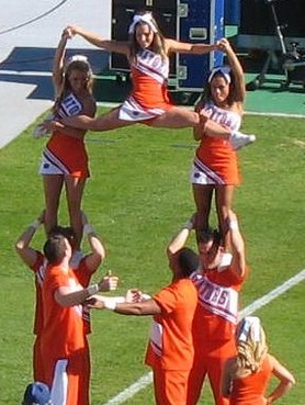 English: Collegiate cheerleaders perform a hig...